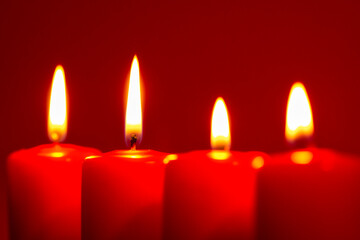 Four burning candles on snow dark red background