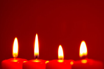 Four burning candles on snow dark red background