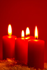 Four burning candles on snow dark red background