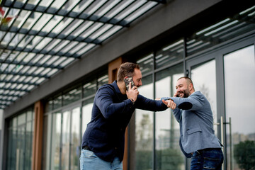 Cheerful businessmen colleagues walking  in front of an office building after work