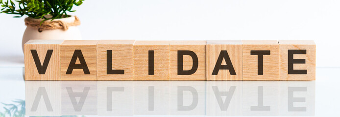 Wooden Blocks with the text: validate. The text is written in black letters and is reflected in the mirror surface of the table.