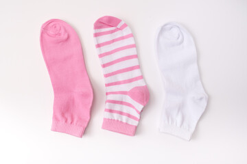 Three socks in pink color gamma, laying from white to pink close up on white background