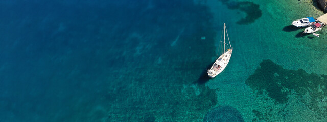 Aerial drone ultra wide photo of beautiful anchored sailboat in tropical exotic bay with emerald crystal clear sea