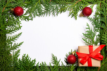 Thuja frame with new year red balls and gift on white background