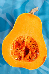 Fresh butternut squash on the blue background. Butternut Pumpkin. Halves of raw orange pumpkin. Contrast photo. Healthy Meal Prep, recipe preparation photo. Seasonal pumpkin cooking
