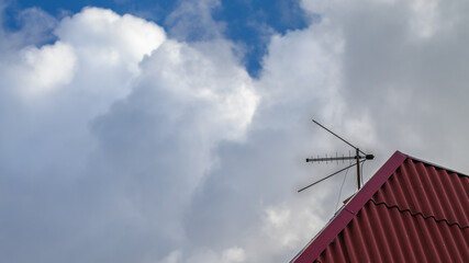 Combined TV antenna mounted on the red roof of the building. TV antenna meter and decimeter.