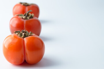 Persimmon fruits lie in a row on a white background.