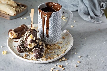 Frozen banana on a stick covered with dark chocolate and crumbs of nuts. A quick, delicious dessert...