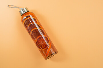 Sport water bottle with sliced red orange inside on orange background