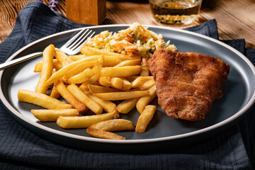 Fried cod fillet with fries and salad.