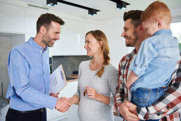 Family and real estate agent shaking hands in new apartment