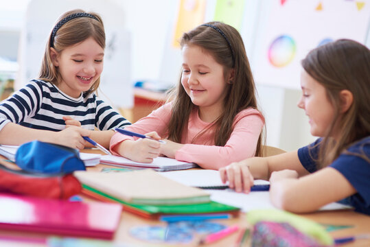 Happy schoolgirls working together in class