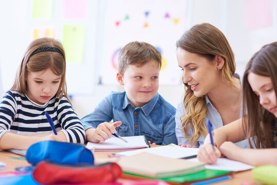 Teacher helping pupils with their tasks in class