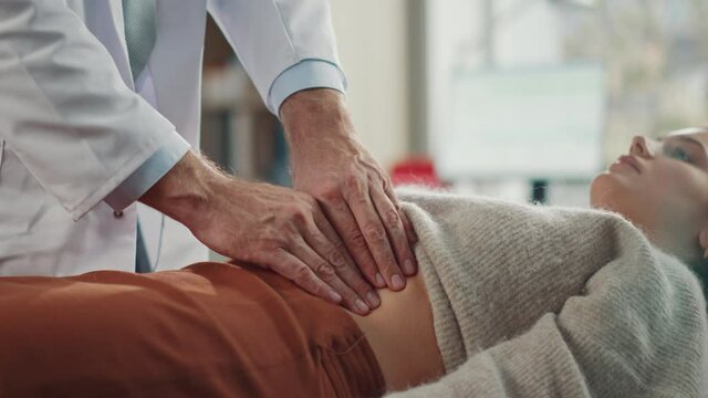 Doctor Consultation Office: Female Patient Lying on a Bed while Family Physician Checks Her Abdomen. Medical Health Care Specialist Localizes Stomach Pain, Identifying Disease, Prescribing Treatment 