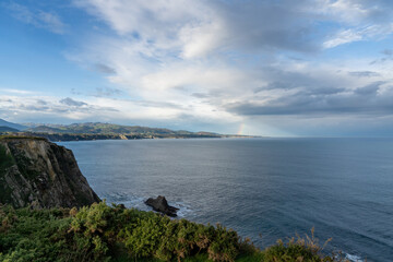 Fototapeta na wymiar jagged and rocky ocean coast with cliffs and a rainbow