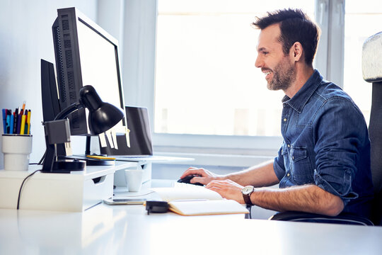 Smiling man working on computer at desk in office