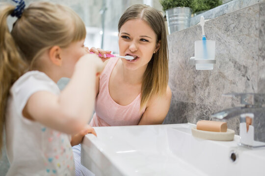 Mother and daughter brushing teeth in bathroom