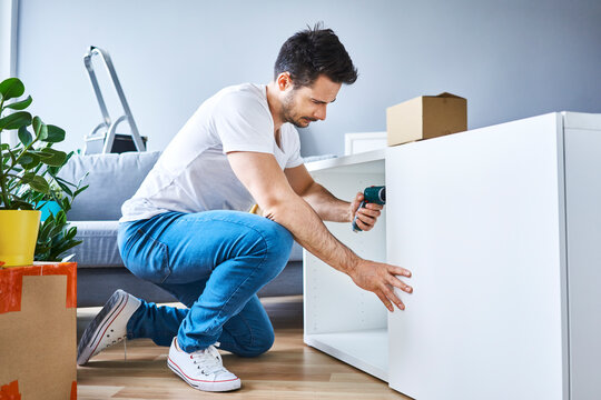 Man assembling a bookshelf in new apartment