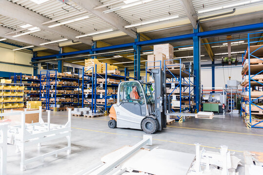 Man on forklift in factory warehouse - Powered by Adobe