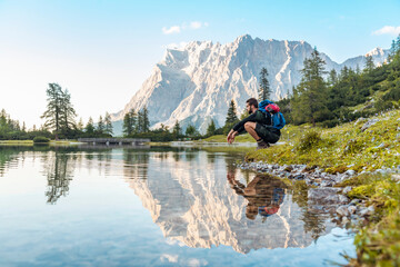 Austria, Tyrol, Hiker taking a break, crouching by the lake