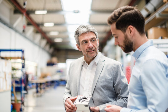 Businessmen during meeting with a product in production hall