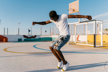 Carefree young man dancing in sports court against clear sky
