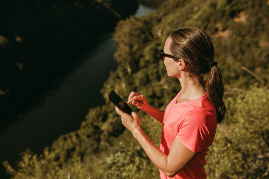 Woman using mobile phone while standing on mountain at Sierra De Hornachuelos, Cordoba, Spain