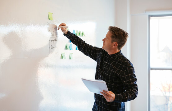 Businessman in office writing on whiteboard