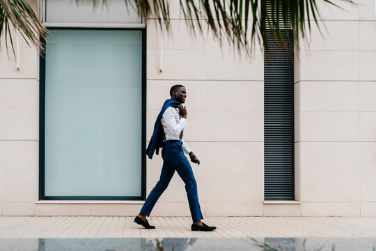 Smiling male African professional walking on sidewalk in city