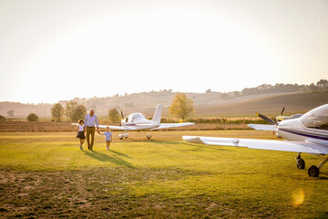 Grandfather walking with grandchildren at airfield on sunny day
