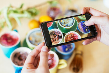 Woman taking smartphone picture of various colorful drinks