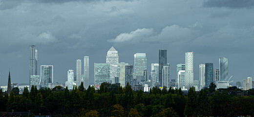Obraz premium Canary Wharf Skyline and Trees Under Dark Cloud Looking North 