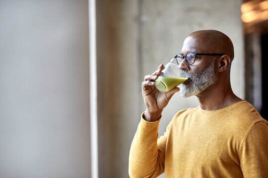 Mature businessman in office drinking a smoothie