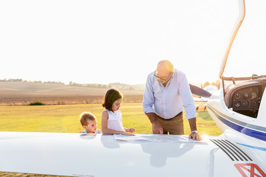 Grandchildren and grandfather looking at map on sunny day