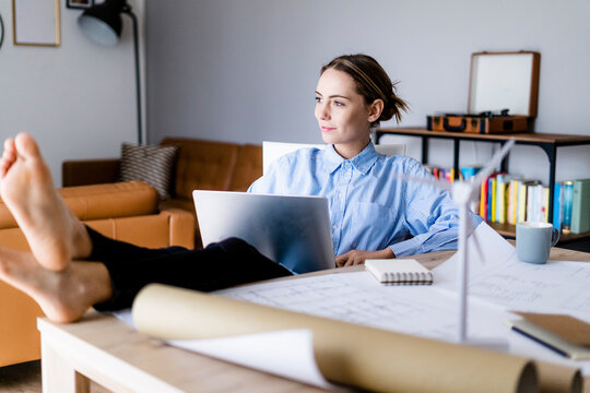 Woman in office working on laptop with feet on table