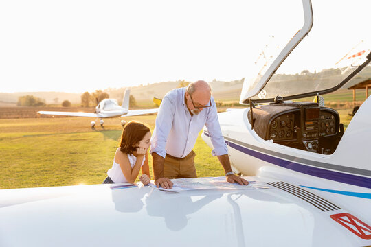 Grandfather and little girl looking at map on sunny day