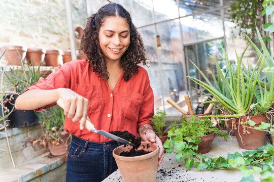 Mature woman putting soil while standing in garden shed