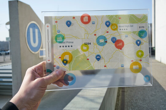 Hand holding futuristic device with digital icons and map in the city