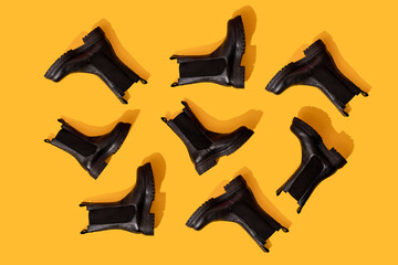 Studio shot of black leather boots against yellow background