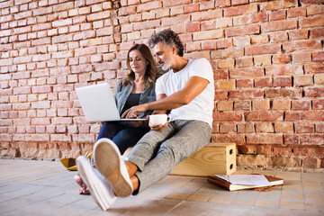 Businessman and woman sitting in a loft, using laptop, founding a start-up company