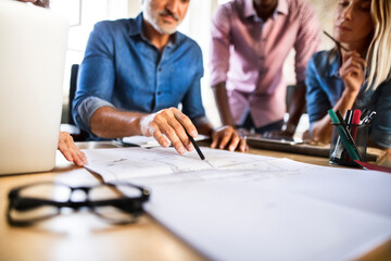 Colleagues discussing blueprint at desk in office