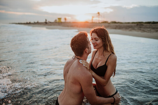 Couple wearing swimwear doing romance in water at beach