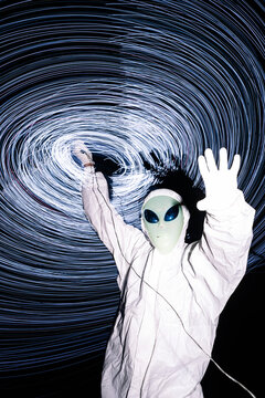 Man in white alien costume standing under light trails at night