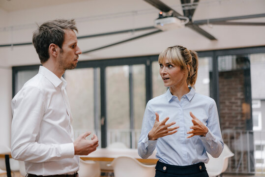 Businessman and woman standing in office, discussing