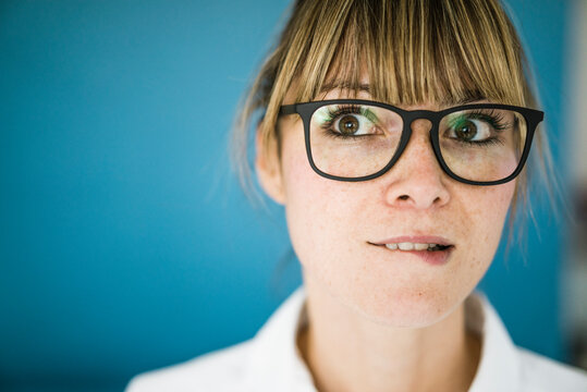 Portrait of woman with glasses biting on her lip