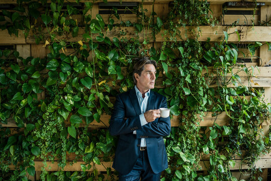 Businessman with cup of coffee in green office