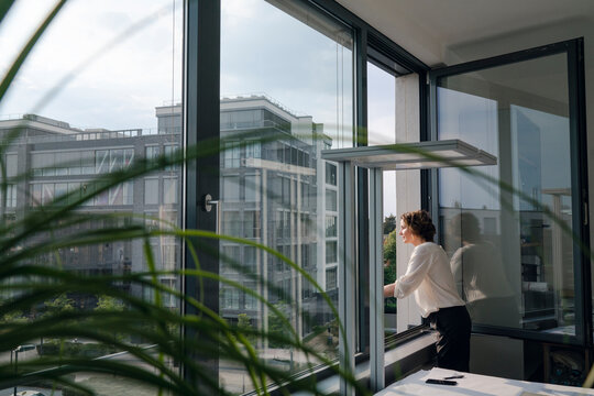 Businesswoman standing in office, looking out of window