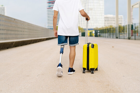 Disabled Young Man Walking With Luggage At Sidewalk In City