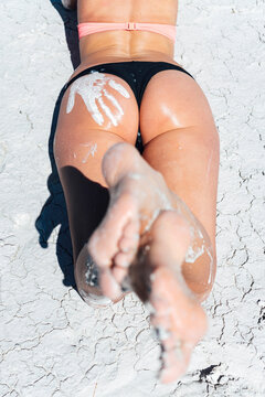 Back of seductive woman wearing bikini lying on white sand at beach