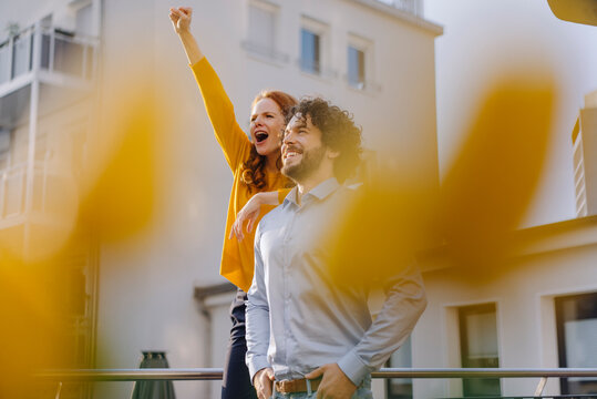 Woman with colleague on roof terrace clenching fist